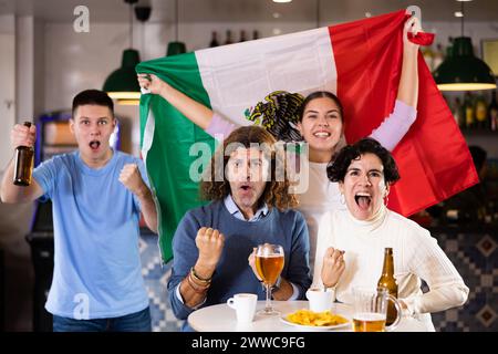 Joyeux fans de l'équipe mexicaine célébrant la victoire au bar de nuit Banque D'Images