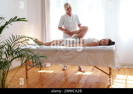 Thérapeute professionnel effectuant des ajustements chiropratiques sur la jambe du patient en salle de traitement Banque D'Images