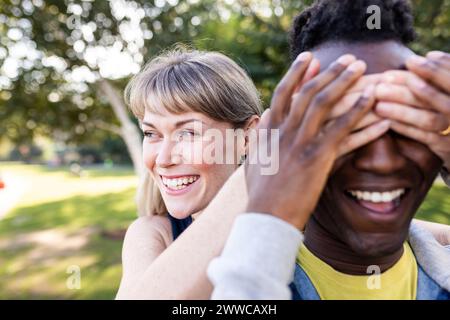 Happy woman covering eyes of friend at park Stock Photo