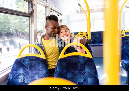 Homme assis avec le bras autour d'un ami dans un bus à impériale Banque D'Images