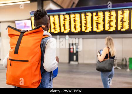 Backpacker avec un ami regardant l'horaire du train Banque D'Images