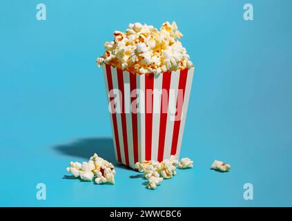 Pop-corn dans un récipient rayé rouge sur fond bleu Banque D'Images