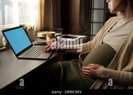 Jeune femme d'affaires enceinte utilisant un ordinateur portable au bureau dans le bureau à domicile Banque D'Images