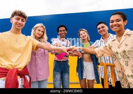 Groupe multi-ethnique de jeunes amis empilant les mains devant le mur Banque D'Images