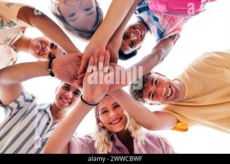 Groupe multi-ethnique de jeunes amis empilant les mains regardant vers le bas la caméra Banque D'Images
