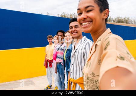 Groupe multi-ethnique de jeunes amis debout souriant devant un mur coloré Banque D'Images