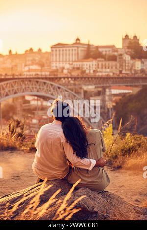 Couple assis devant le pont Dom Luis au coucher du soleil, Porto, Portugal Banque D'Images