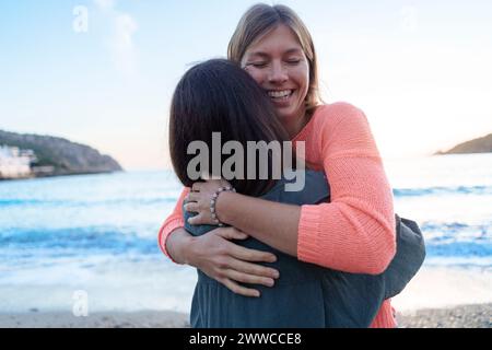 Femme heureuse embrassant un ami sur le rivage à la plage Banque D'Images