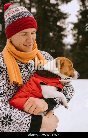 Homme et chien portant des vêtements chauds dans la forêt d'hiver Banque D'Images
