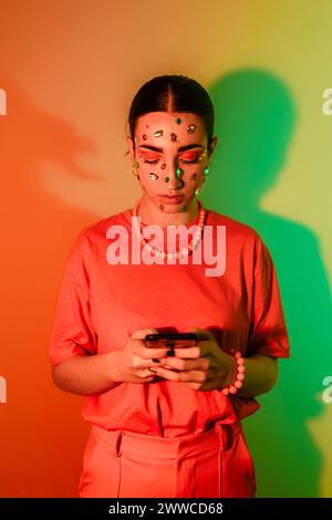 Jeune femme utilisant un téléphone intelligent sur fond de néon Banque D'Images