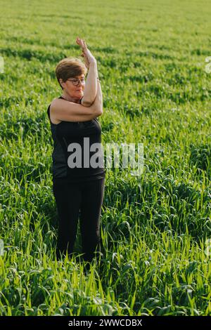 Femme senior retraitée en forme pratiquant le yoga dans la prairie Banque D'Images