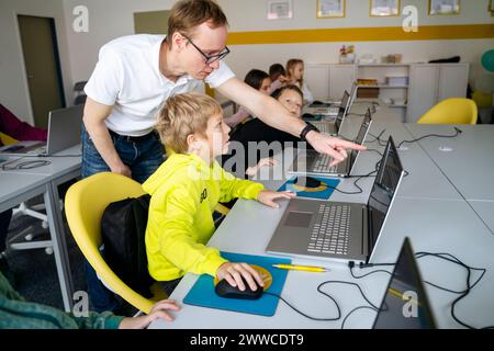 Professeur pointant le doigt sur un ordinateur portable enseignant le codage garçon en classe Banque D'Images