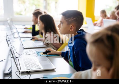 Garçon dédié utilisant le codage informatique d'apprentissage d'ordinateur portable dans la salle de classe Banque D'Images