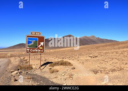 19 novembre 2023 - Morro Jable, Jandia, Fuerteventura en Espagne : route de gravier, poussiéreuse avec de hautes montagnes volcaniques en arrière-plan Banque D'Images