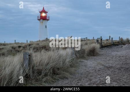 Allemagne, Schleswig-Holstein, List, sentier de sable au crépuscule avec le phare de List West en arrière-plan Banque D'Images