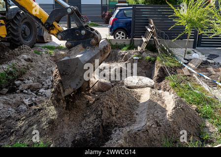 Utilisation d'une excavatrice pour enterrer une fosse septique en béton de 10 m3 située dans le jardin à côté de la maison. Banque D'Images