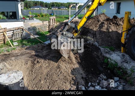 Utilisation d'une excavatrice pour enterrer une fosse septique en béton de 10 m3 située dans le jardin à côté de la maison. Banque D'Images