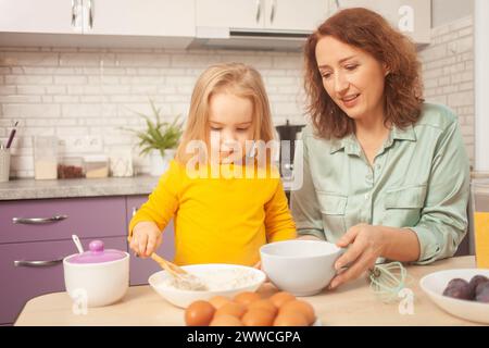 grand-mère et petite-fille font du gâteau dans la cuisine, famille heureuse, femme et enfant sourient. Banque D'Images
