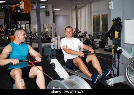 Les hommes effectuent des exercices dans le gymnase. Coach et gros client, taille du modèle plus, corps positif. Un homme construit des muscles et perd du poids. Banque D'Images