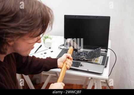 Un employé de bureau a brisé un ordinateur portable, détruit un ordinateur. Colère haine, irritation. Erreur, frein, dysfonctionnement, ne veut pas travailler. Mauvaises émotions. dep Banque D'Images