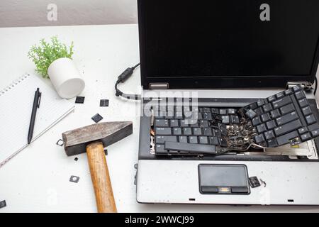 L'homme a détruit l'ordinateur portable avec un marteau. Travail nerveux, ordinateur buggy, erreurs, Internet lent, non sauvegardé dans le jeu, texte imprimé, accroché. Mauvais vieux comput Banque D'Images
