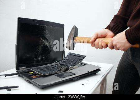L'homme a détruit l'ordinateur portable avec un marteau. Travail nerveux, ordinateur buggy, erreurs, Internet lent, non sauvegardé dans le jeu, texte imprimé, accroché. Mauvais vieux comput Banque D'Images