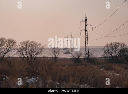 Paysage d'hiver avec des lignes à haute tension sur le fond de ciel bleu Banque D'Images