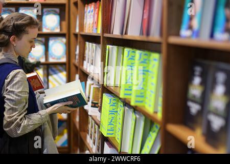 Leipzig, Allemagne. 23 mars 2024. Un visiteur du salon lit à la Foire du livre de Leipzig. Plus de 2000 exposants de 40 pays présentent leurs nouveaux produits à la réunion de printemps de l'industrie du livre. Crédit : Jan Woitas/dpa/Alamy Live News Banque D'Images