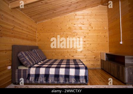 La chambre est décorée avec des lambris de bois chaleureux et un lit doux et accueillant. Un beau lustre fournit un éclairage doux. Banque D'Images