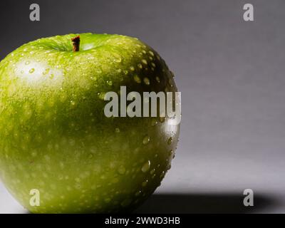 Une délicieuse pomme verte fraîche et croustillante avec des gouttes d'eau. Banque D'Images