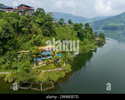 Vue aérienne du lac Begnas le troisième plus grand lac du Népal. Nature sauvage et arbres avec des maisons entourent le lac, bateaux népalais typiques dans l'eau Banque D'Images