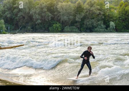 Un jeune surfeur portant une combinaison surfe dans la rivière Aar à marée haute. Banque D'Images