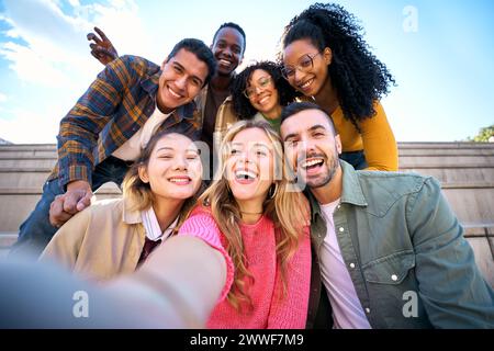Groupe d'amis multiethniques prenant selfie avec téléphone mobile intelligent à l'extérieur Banque D'Images