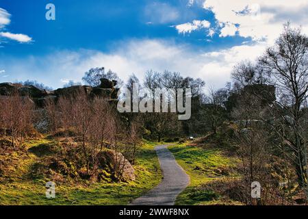 Sentier pittoresque à travers un parc luxuriant avec des affleurements rocheux et un ciel bleu éclatant avec des nuages moelleux à Brimham Rocks, dans le North Yorkshire Banque D'Images