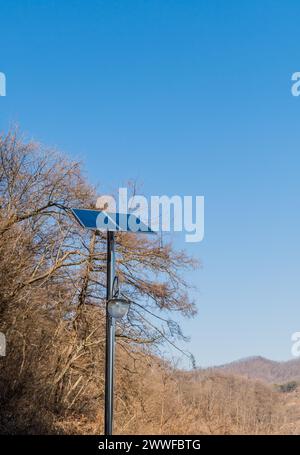 Petit panneau solaire sur le dessus du poteau chromé devant des arbres sans feuilles contre le ciel bleu à Buan, Corée du Sud Banque D'Images