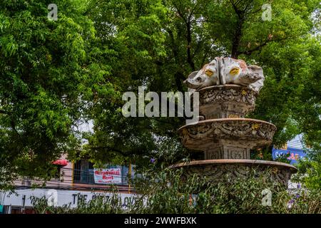 Une fontaine détaillée contre la verdure urbaine et les façades de magasins, à Chiang mai, Thaïlande Banque D'Images