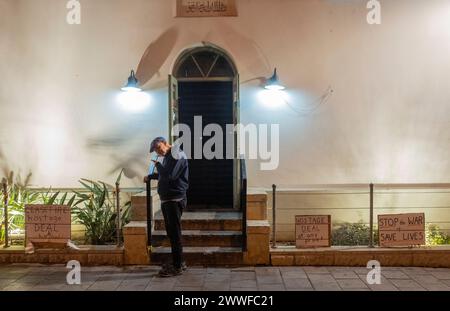Tel Aviv, Israël. 23 mars 2024. Un israélien utilise son téléphone portable alors qu'il se tient près de pancartes de protestation à tel Aviv, Israël, le 23 mars 2024 dans la nuit lors d'une manifestation de masse appelant à évincer le premier ministre Benjamin Netanyahu, à ramener les otages détenus par le Hamas chez eux et à la paix. Des dizaines de milliers d’Israéliens sont descendus dans les rues à tel Aviv et dans de nombreuses autres villes d’Israël alors que la guerre contre le Hamas dans la bande de Gaza entre dans son sixième mois. Photo de Jim Hollander/UPI crédit : UPI/Alamy Live News Banque D'Images