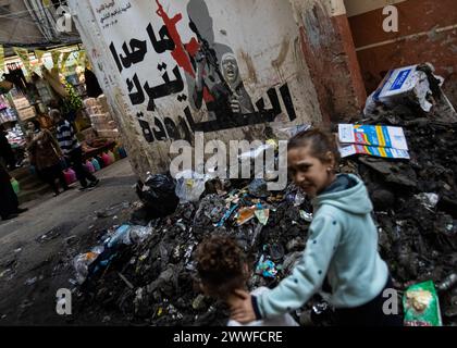 Beyrouth, Liban. 19 mars 2024. Des enfants palestiniens du camp de réfugiés de Shatilla, Beyrouth, Liban, marchent devant une murale représentant la mère du combattant palestinien tué Ibrahim al-Naablusi tenant un M4 lors de ses funérailles en Cisjordanie le 19 mars 2024. Le texte se lit comme suit : « personne ne quitte l’arme ». Le camp de réfugiés de Shatilla abrite environ 30 000 Syriens et Palestiniens déplacés. (Photo de Collin Mayfield/Sipa USA) crédit : Sipa USA/Alamy Live News Banque D'Images