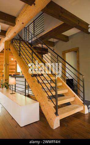 Escaliers en bois avec garde-corps en fer forgé noir et longue table d'armoire à l'intérieur d'une maison en bois de style contemporain, Québec, Canada Banque D'Images