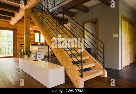 Escaliers en bois avec garde-corps en fer forgé noir et longue table d'armoire à l'intérieur d'une maison en bois de style contemporain, Québec, Canada Banque D'Images