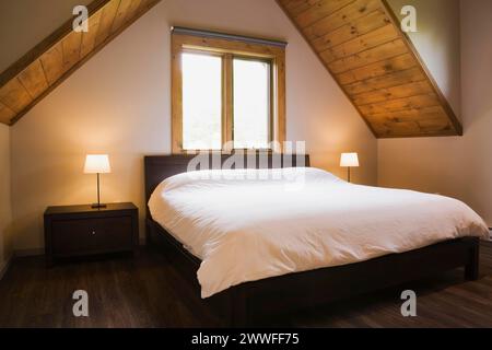 Lit king size dans la chambre principale à l'étage à l'intérieur de la maison en rondins de style contemporain, Québec, Canada Banque D'Images