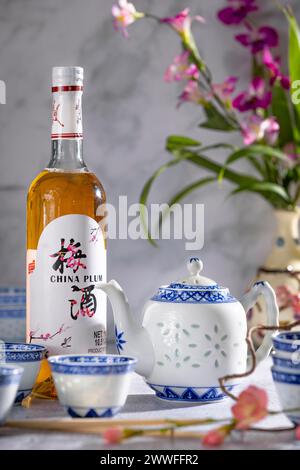 Service à thé asiatique avec des motifs bleus et une bouteille de vin de prune de Chine Banque D'Images