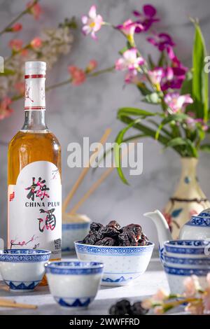 Service à thé asiatique aux motifs bleus, une bouteille de vin de prune chinois et des fruits secs Banque D'Images