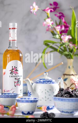 Service à thé asiatique aux motifs bleus, une bouteille de vin de prune chinois et des fruits secs Banque D'Images