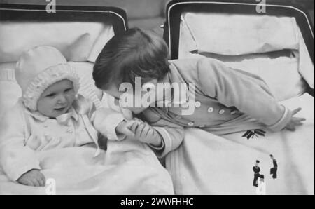 Une photographie datant d'environ 1951 montre une jeune princesse Anne et Charles III dans leurs landaus (poussettes). Charles est vu penché de sa poussette pour regarder et tenir la main de sa sœur, illustrant un lien précoce entre les frères et sœurs royaux. Banque D'Images