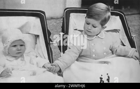 Une photographie de 1951 montre un jeune prince Charles III et la princesse Anne dans leurs landaus (poussettes), Charles vu tenant la main de sa sœur cadette. Cette image capture un moment touchant entre le futur roi et sa sœur. Banque D'Images