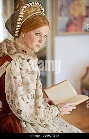 Femme, reine et livre avec portrait pour la renaissance, la royauté esthétique et la lecture dans la chambre du palais. Monarque, personne riche et robe élégante pour Banque D'Images
