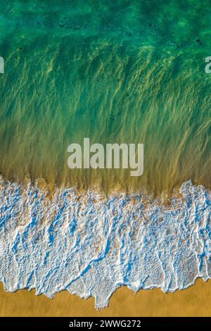 Vue aérienne basse d'une vague se brisant sur la plage au parc Sandy Beach sur l'île d'Oahu, Hawaï. Banque D'Images