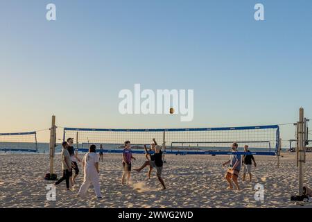 Les joueurs profitent d'une partie amicale de volley-ball sur la plage au coucher du soleil. Banque D'Images