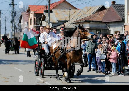 Bucarest, Roumanie. 23 mars 2024. Les personnes dans des charrettes à chevaux participent à un défilé de beauté pour chevaux pendant la célébration de la traditionnelle fête "Tudorita", également connue sous le nom de Pâques des chevaux, à Targoviste, à 80 km au nord de Bucarest, Roumanie, le 23 mars 2024. Pâques des chevaux est célébrée par la communauté bulgare locale et symbolise le début du travail agricole dans la nouvelle année. Crédit : Cristian Cristel/Xinhua/Alamy Live News Banque D'Images